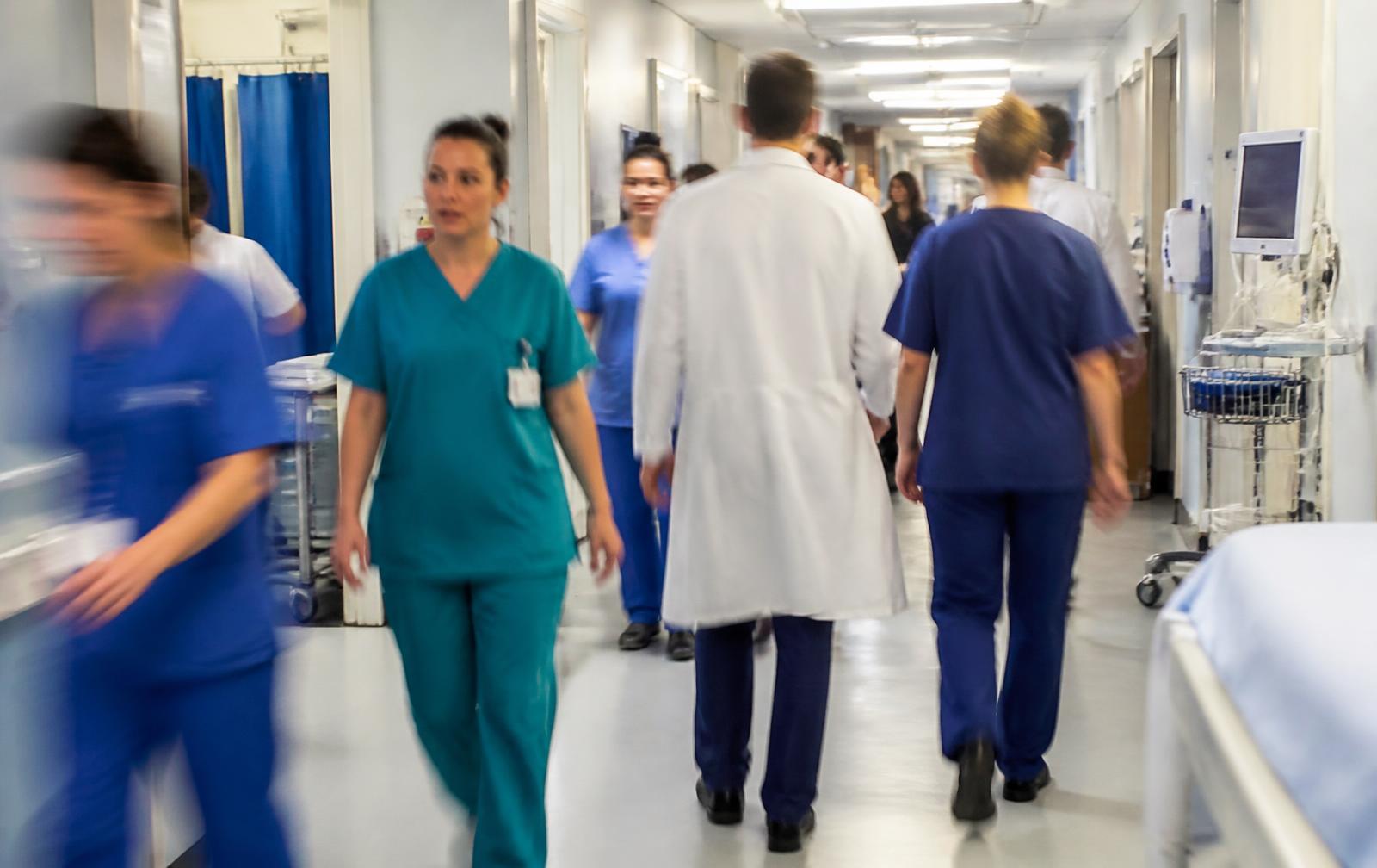 Nurses and doctors walking through a busy hospital corridor
